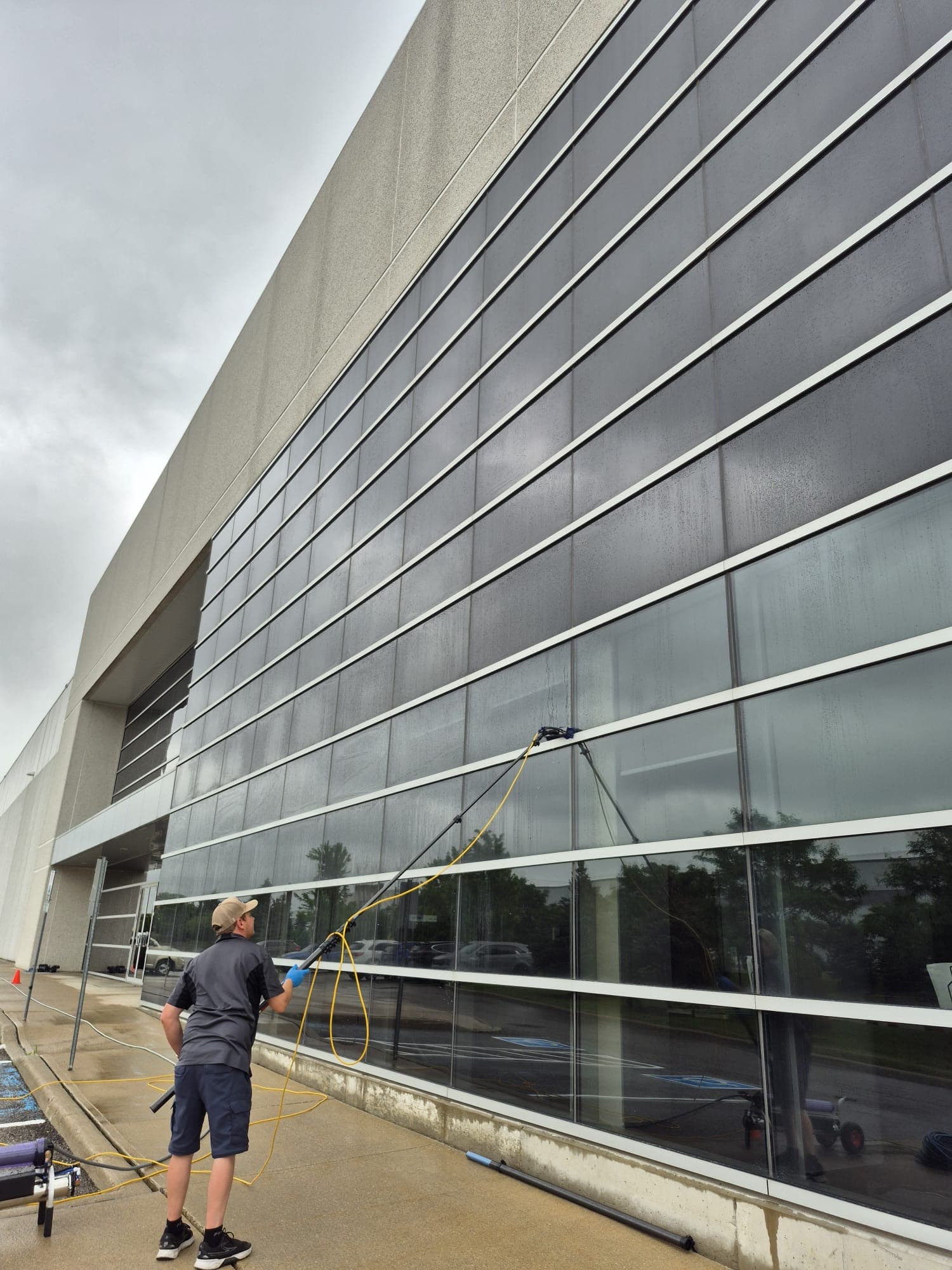 Technician using a water-fed pole on a high-rise glass wall